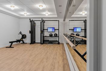 A gym with a wooden floor and a variety of equipment including a squat rack, a bench, and a barbell.